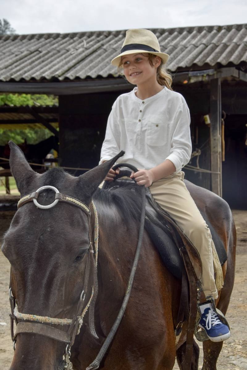 Criança a cavalo na área verde do Casarão Penedo