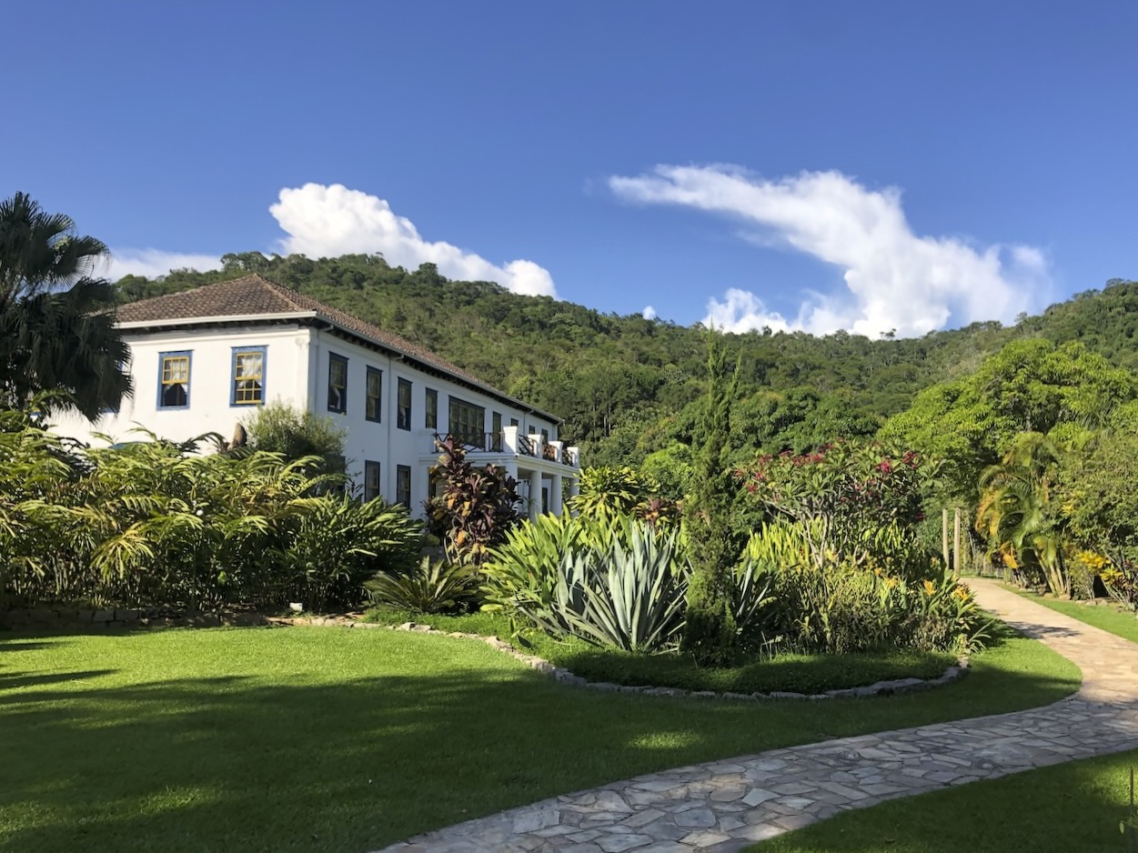 Outdoor wedding ceremony at Casarão Penedo — bride walking towards guests with historic façade in background