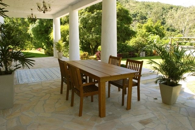 Varanda coberta do Casarão Penedo com mesa e vista para jardim