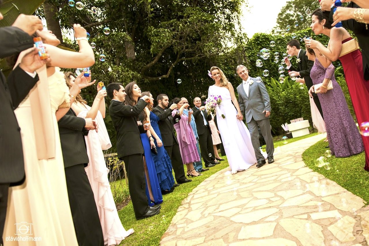 Noivos saindo da cerimônia entre convidados com bolhas de sabão no Casarão Penedo
