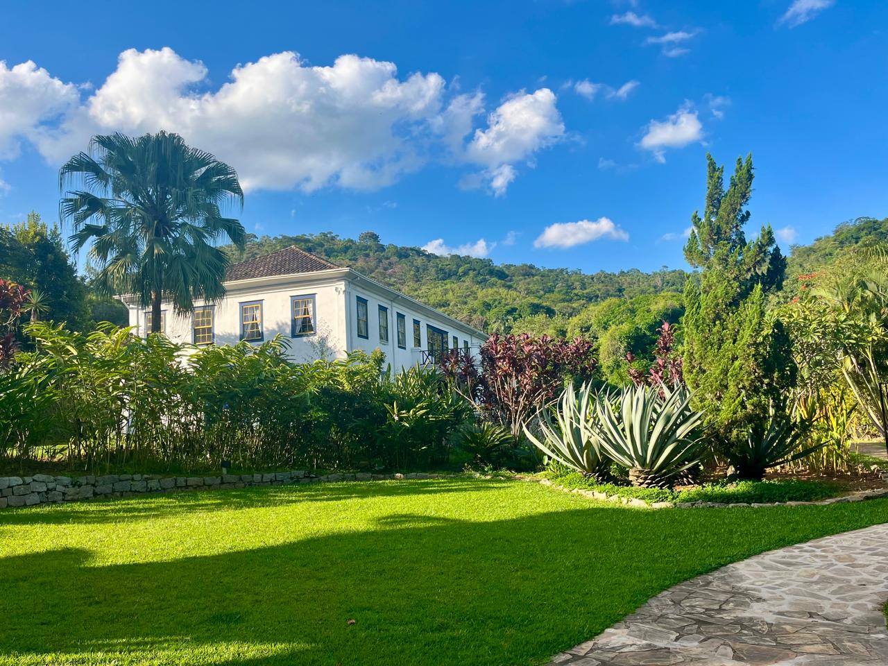 Fachada do Casarão Penedo com gramado e jardins tropicais