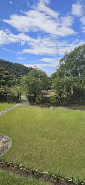 Gramado verde com céu azul e serra ao fundo no Casarão Penedo