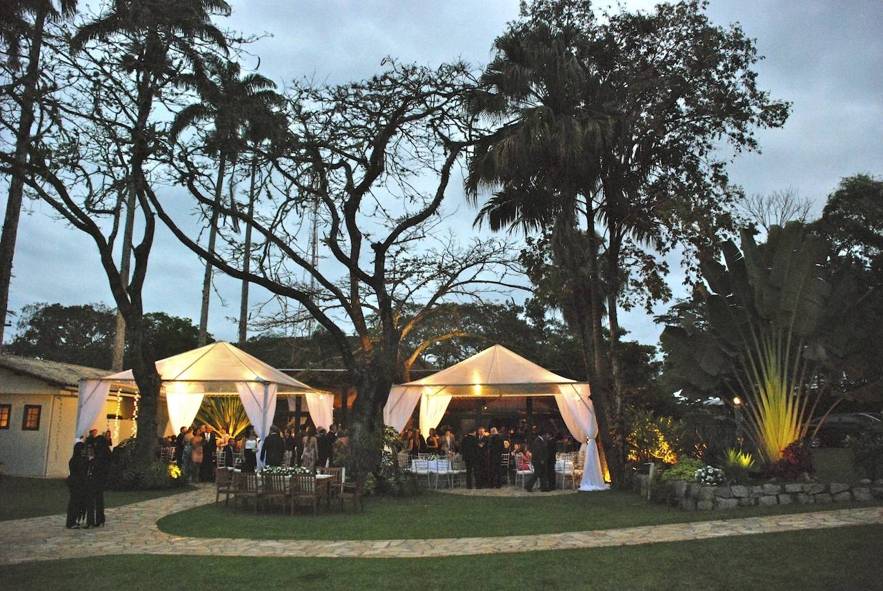 Illuminated tents under century-old trees at Casarão Penedo at night