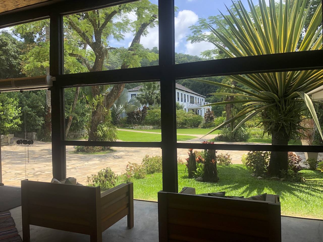 Interior view of Casarão Penedo's Reception Area with glass walls, furnishings and views of gardens and historic façade